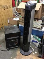 Photo showing both the RCIN electric heater and Seville Classics electric tower fan placed side by side in a cluttered environment.
