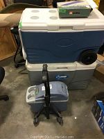 Two large coolers stacked, blue and white Coleman on top, gray underneath, and Mobicool mini cooler with handle in front on the ground