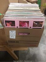 Box filled with various vinyl LP records stored vertically, showing different cover arts including close-up images of performers.