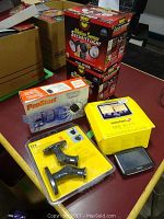 Lot contents showing boxed Motion Sensor Security Lights, ProStart car starter boxed, TomTom GPS box, speaker mounts.