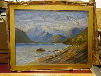 Framed vintage oil painting showing a lake with mountains and trees, slight canvas cracking, gold frame with wear.