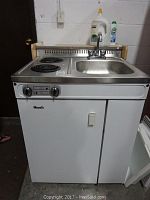 Front view of entire Woods kitchen unit showing cooktop, sink and lower cabinet doors