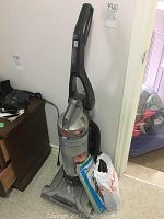 Front view of Hoover WindTunnel upright vacuum showing handle, dustbin, and base with power cord on the side.