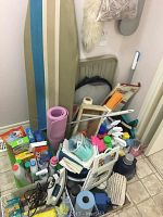 Image showing overall lot arrangement including ironing board, step stool, wooden washboard, and various bottles and cleaning items piled on floor.