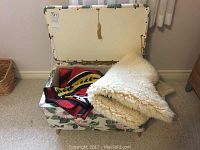 Blanket box open showing lambskin rug and woven blanket inside.