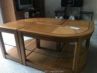 Full view of wood coffee table with two interlocking pieces and lower glass shelf on castors.