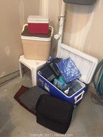 Wide view showing three hard coolers stacked and various insulated bags on the floor and inside the blue cooler