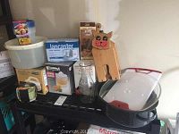 Photo showing boxed Kenmore juicer, Lancaster food chopper, electric can opener, electric grater, wooden cutting board shaped like a rabbit, and some kitchen jars and containers.