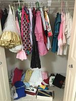 Closet view of multiple ladies square dancing outfits hanging on hangers and several ruffled petticoats/crinolines on floor along with clothing bags.