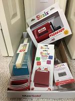 Overview of the lot including Sizzix Sidekick machine, dies, cutting pads, and scrap cardstock pack all arranged in a box.