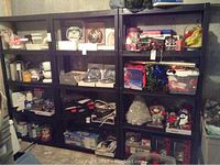 Front view of three black plastic shelving units filled with various household items and decorations