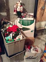 Wide view showing stacked totes and boxes containing Christmas decorations with Santa figure on top.