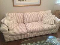 Full view of the 83 inch Bauhaus style sofa with beige and white striped upholstery and five matching pillows arranged on top.