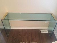 Full view of the rectangular glass sidebar table with yellow brass accents on the top corners, showing its transparent design and wooden floor beneath.