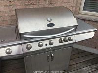 Full front view of the Patio Range gas BBQ grill showing the hood with thermometer, control knobs, and storage cabinet below.