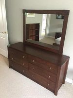 Front view of dark brown wooden dresser with attached rectangular mirror
