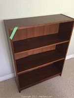 Front angled view of the brown wood veneer bookcase showing three shelves and minimal wear.