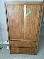 Front view of the Thomasville armoire showing two large doors on top and two drawers below. Wood veneer surface with signs of wear.