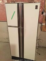 Closed exterior view of the white General Electric refrigerator, showing shape and door handles.