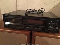 Front view of black Denon DCD-1520 compact disc player showing the front loading CD tray, digital display, and multiple playback controls with a power cord on top.