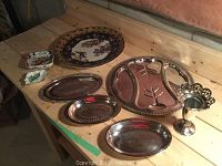 Photo showing various decorative plates and silver-tone plated trays and serving items on a table.