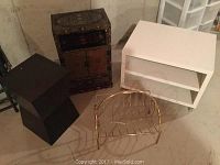 Overview of four decorative pieces including the Asian-inspired cabinet, white veneer stand, black geometric stand, and brass stand on floor.