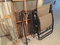 Photo showing beige lawn chair, chaise lounger, foldable baby gate, metal crutches, and wooden canes grouped against a wall.