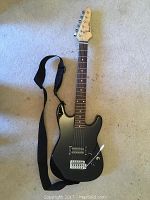 Full length of black Rok Axe electric guitar with strap showing body, neck, and headstock.