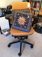 Front view of tan Steelcase office chair with two decorative celestial-themed throw pillows placed on seat