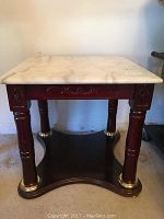 Marble end table with white marble top, wooden legs with gold accents, decorative carvings. Front-facing view.