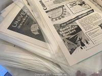 Stack of old magazine ads in plastic sleeves featuring brands like Canon and Campbell's Soup.