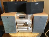 Front view of Sony micro hi-fi system with two beige front speakers and two black smaller speakers on top.