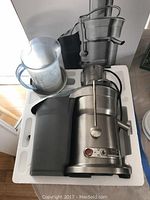 Top front diagonal view of Breville juicer and clear pitcher in packaging foam with box showing.