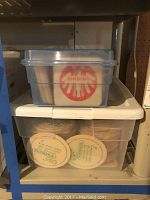 Plastic containers filled with stacks of round and square vintage beer coasters showing logos such as Germania and Binding Bier.