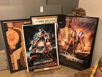 Four framed movie posters including Army of Darkness, The Time Machine, Buffy the Vampire Slayer, and a vintage poster in background with a black Time Machine cap on top.