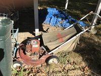 Full side view of the Snapper Hi Vac lawnmower showing the rusted red metal body and attached fabric grass catcher bag resting on the ground.