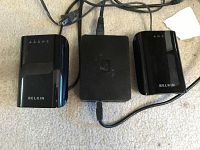Three black adapters placed on carpet - two Belkin Powerline AV adapters and one Ethernet adapter with cables attached