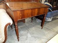 Side view of the vintage wood Paymasters desk showing turned legs and rectangular shape.
