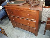 Front view of vintage wood dresser with three drawers and wooden knob handles.