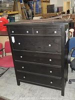 Front view of tall black wooden dresser showing 6 drawers and wooden knobs