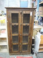 Front view of closed bookshelf showing two paneled doors with metal grille inserts and ring pulls