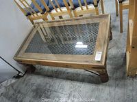 Full view of rectangular glass top coffee table with wooden frame and patterned metal mesh insert showing turned legs.
