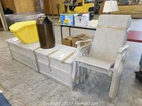 Side view showing one white patio chair next to two deck storage bins, with visible weathering and some dirt marks.