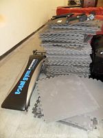 Total Gym bench and stacked grey foam mats side view