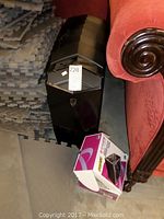 Black Alienware Aurora tower beside red sofa and boxed power supply