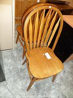 Pair of wooden oak chairs showing curved slatted backs and shaped seats.