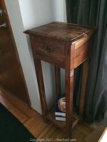 Front angled view of the wooden plant stand showing the drawer and overall structure.