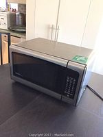 Danby microwave oven closed, showing stainless steel exterior and keypad control panel on the right side.