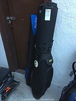 Two golf iron carrying cases side by side, one black BagBoy and one blue Alpha, showing overall condition and size.