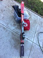 Overview of Head skis leaning on tote with helmets, jacket and red drawstring bag